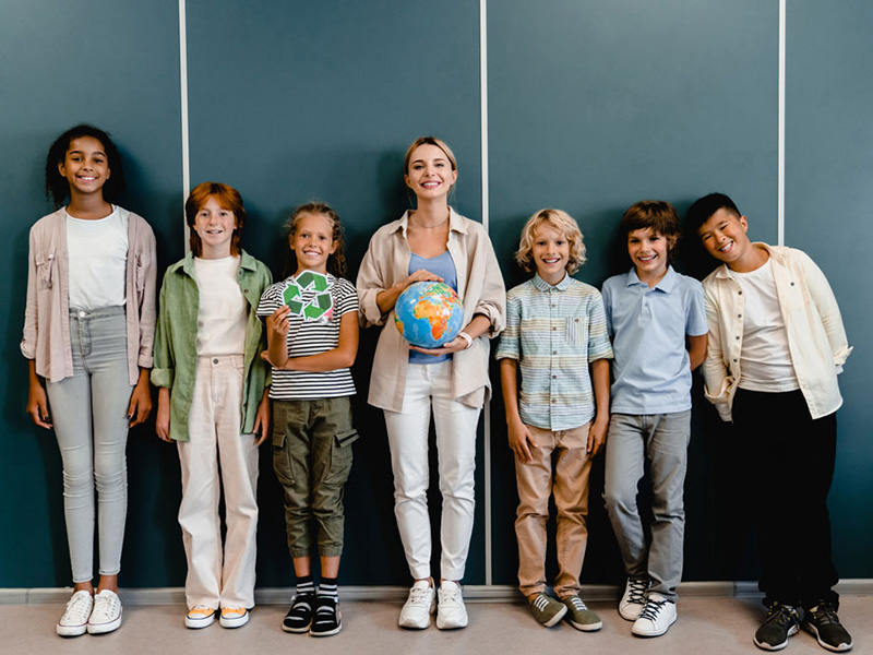 Schoolchildren classmates kids pupils students standing with teacher holding globe and recycling sign at geography school lesson class. Eco-activists. Environment protection.