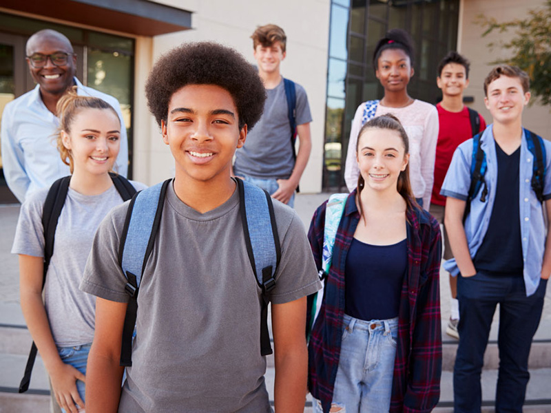 Portrait Of High School Students With Teacher Outside College Buildings
